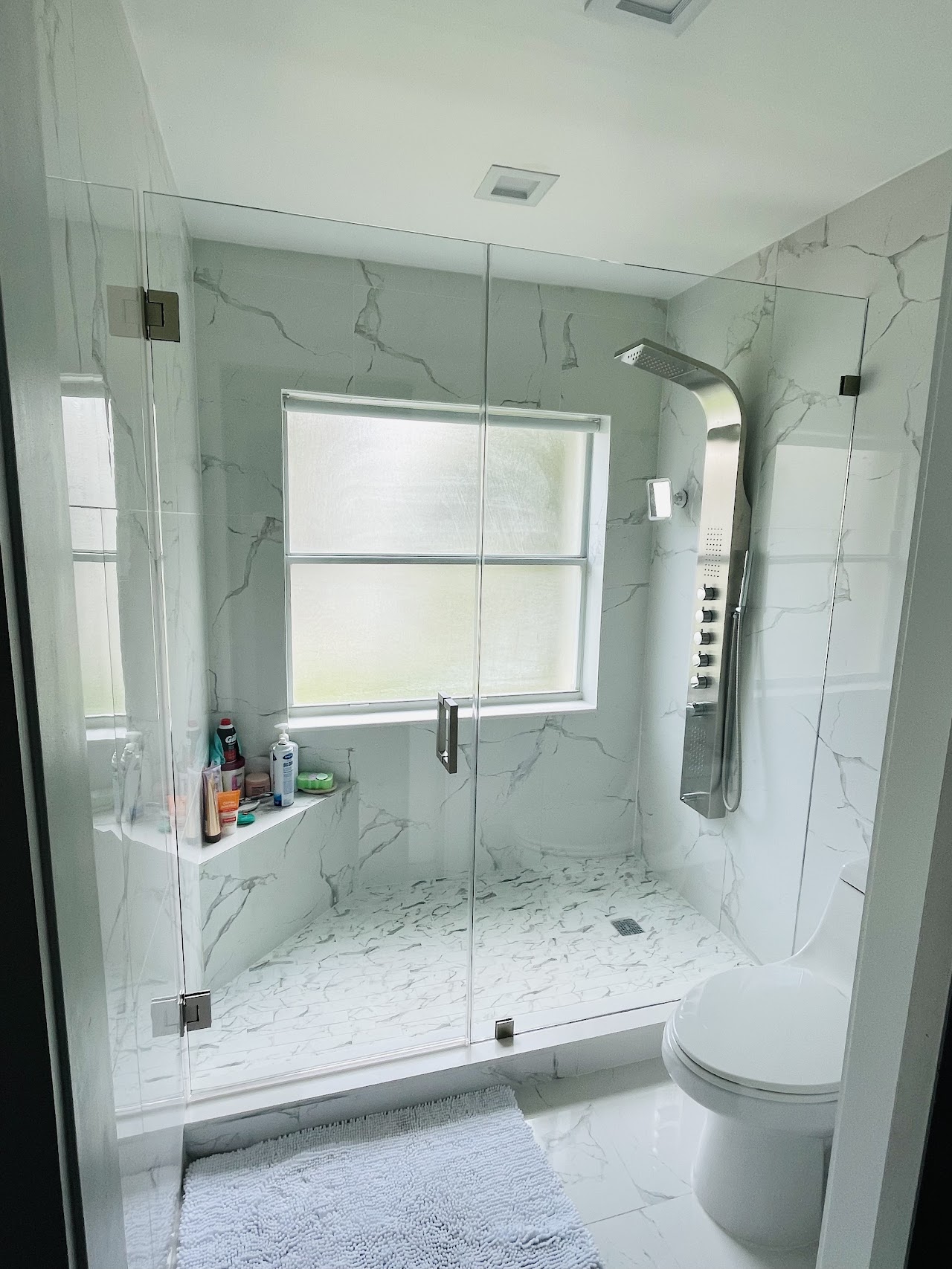 Glass shower enclosure beside a bathroom window