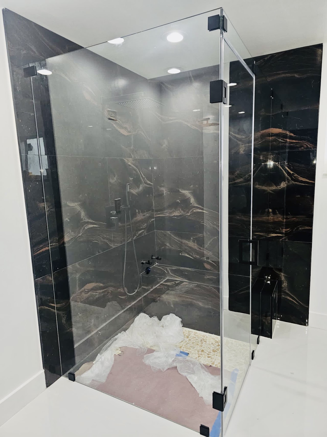 Glass shower enclosure with dark tile