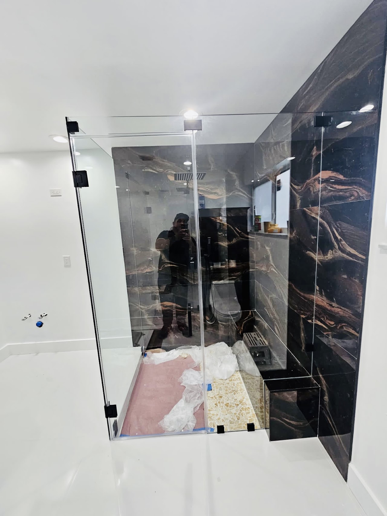 Glass shower door with dark tile walls