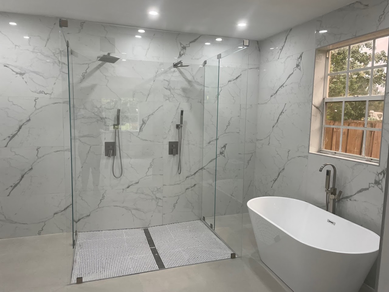 Large glass shower enclosure next to freestanding tub