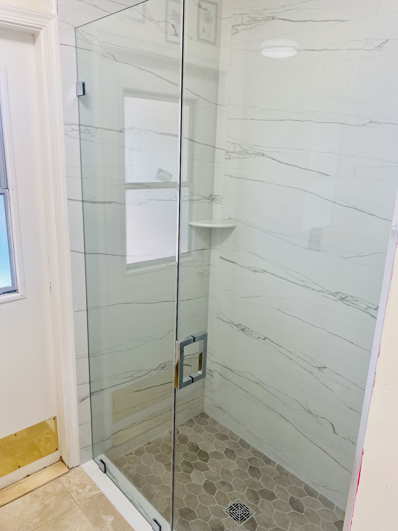 White tile shower behind glass door