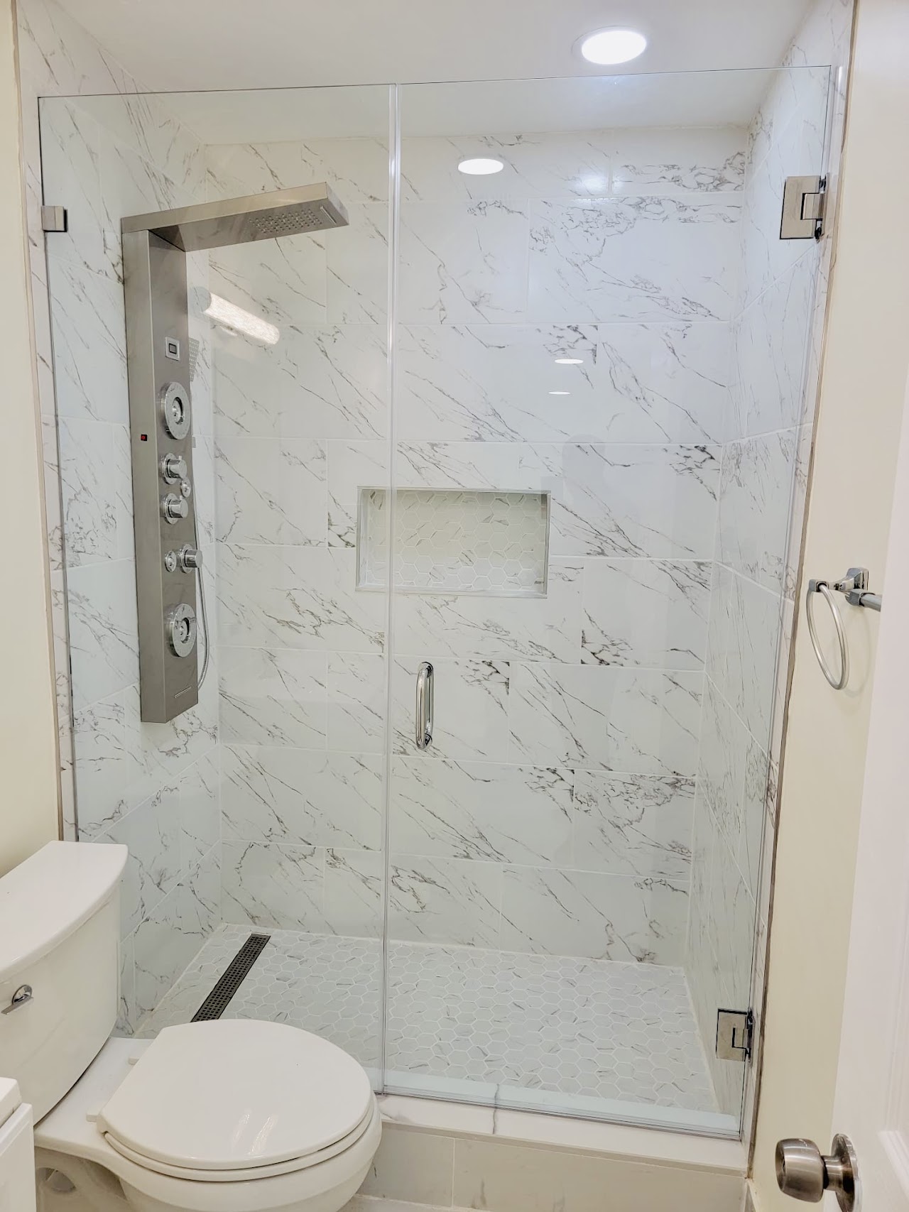 Glass shower door in marble-look bathroom