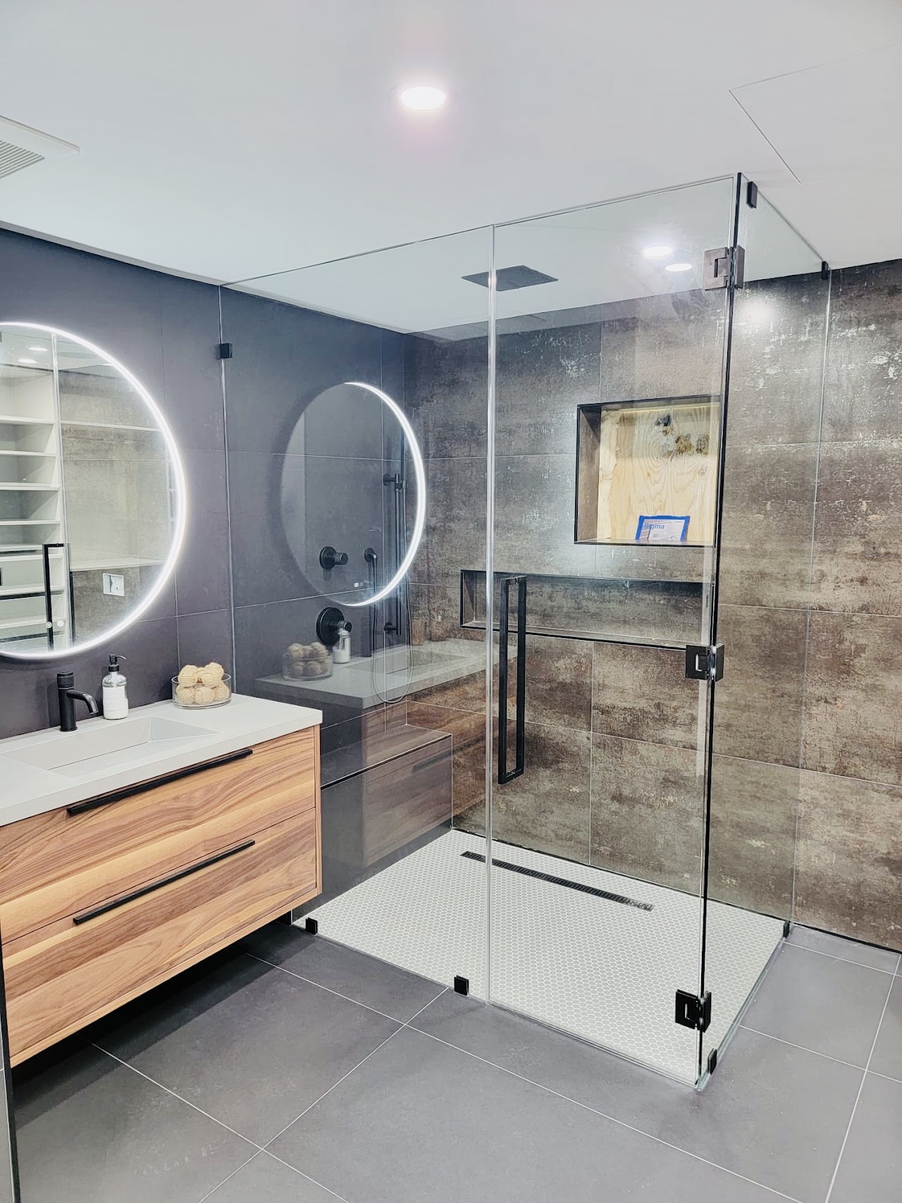 Bathroom with shower glass and round illuminated mirror