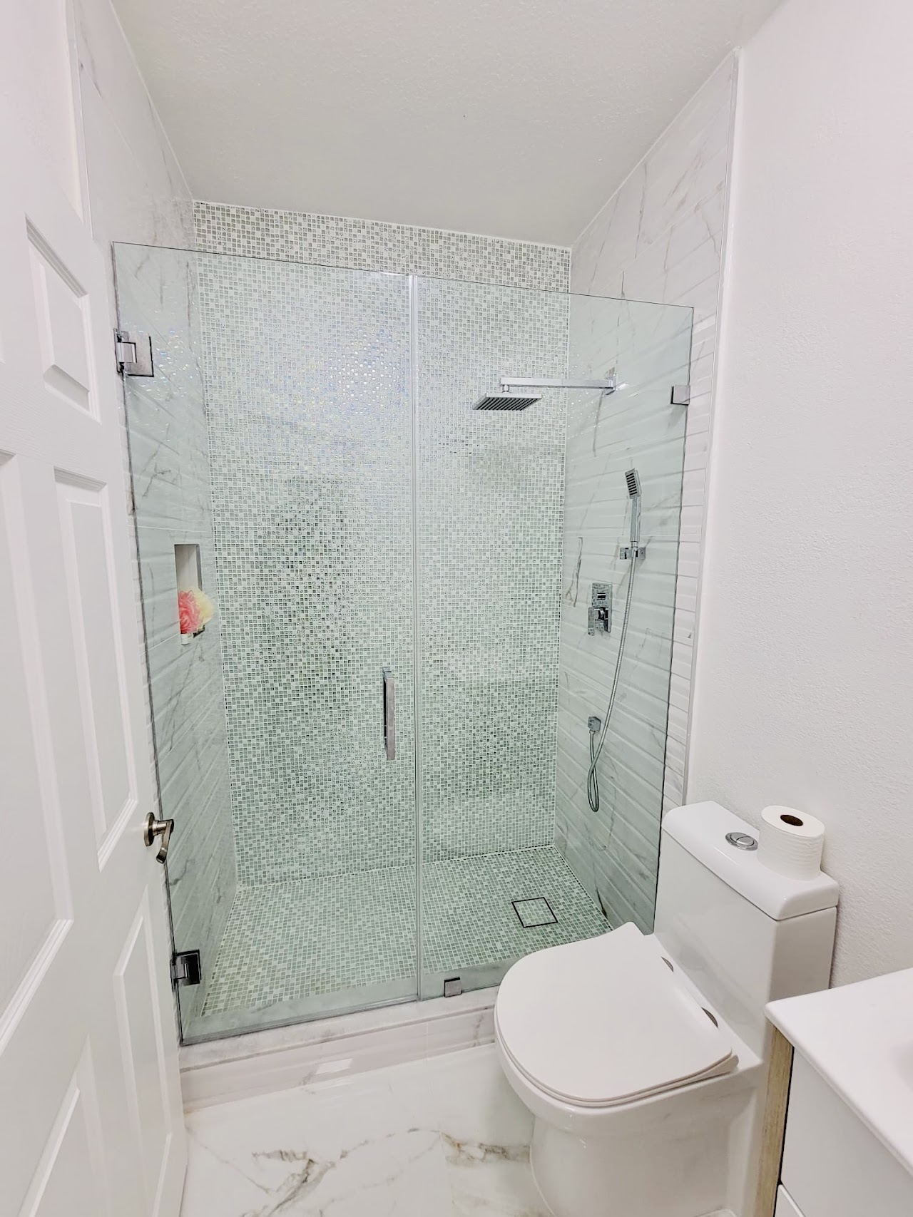 Glass shower enclosure in light bathroom