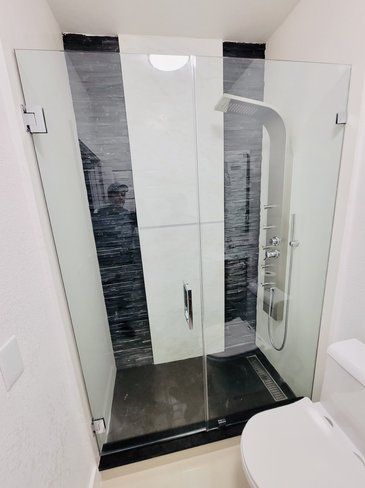 Glass shower in white and dark tile bathroom